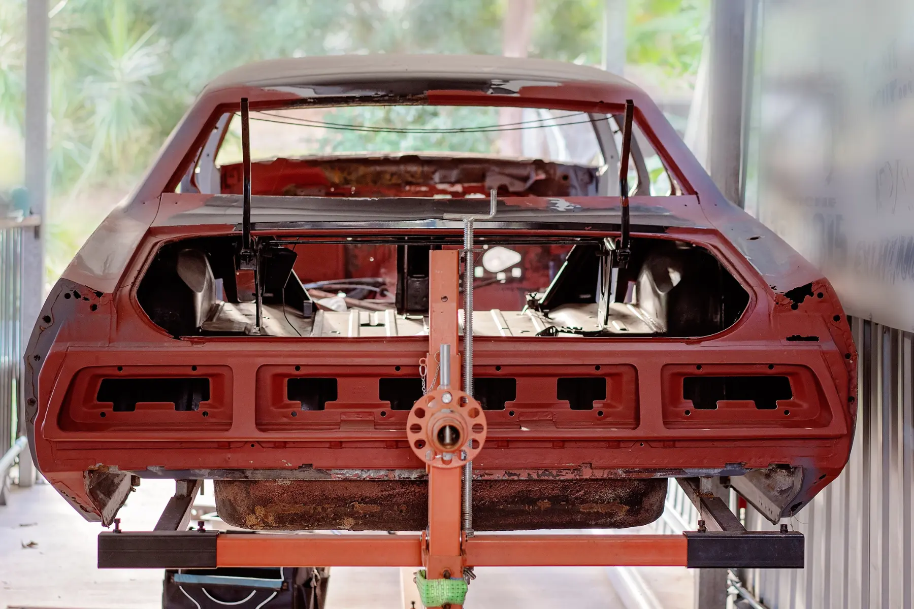 Classic car frame undergoing restoration on a rotisserie stand in a garage