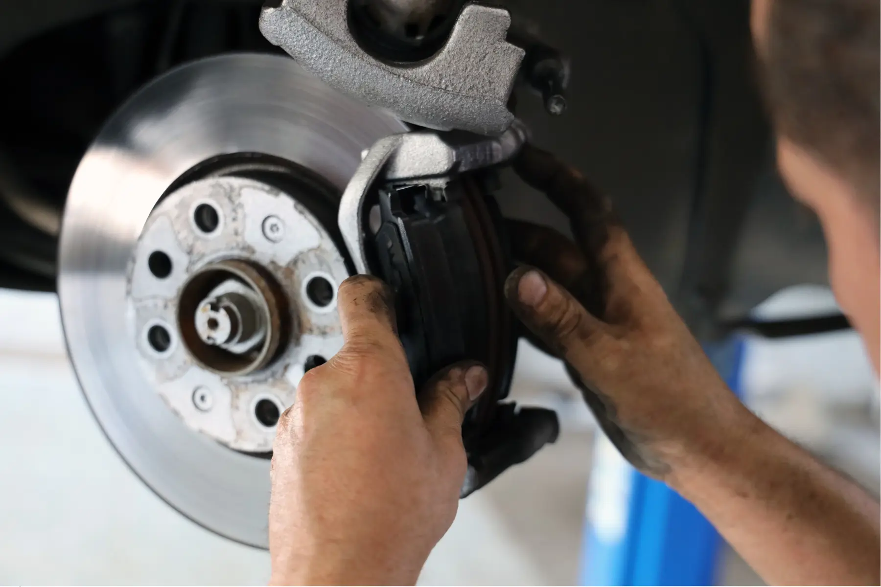 Mechanic handling a brake pad while working on a vehicle’s brake assembly